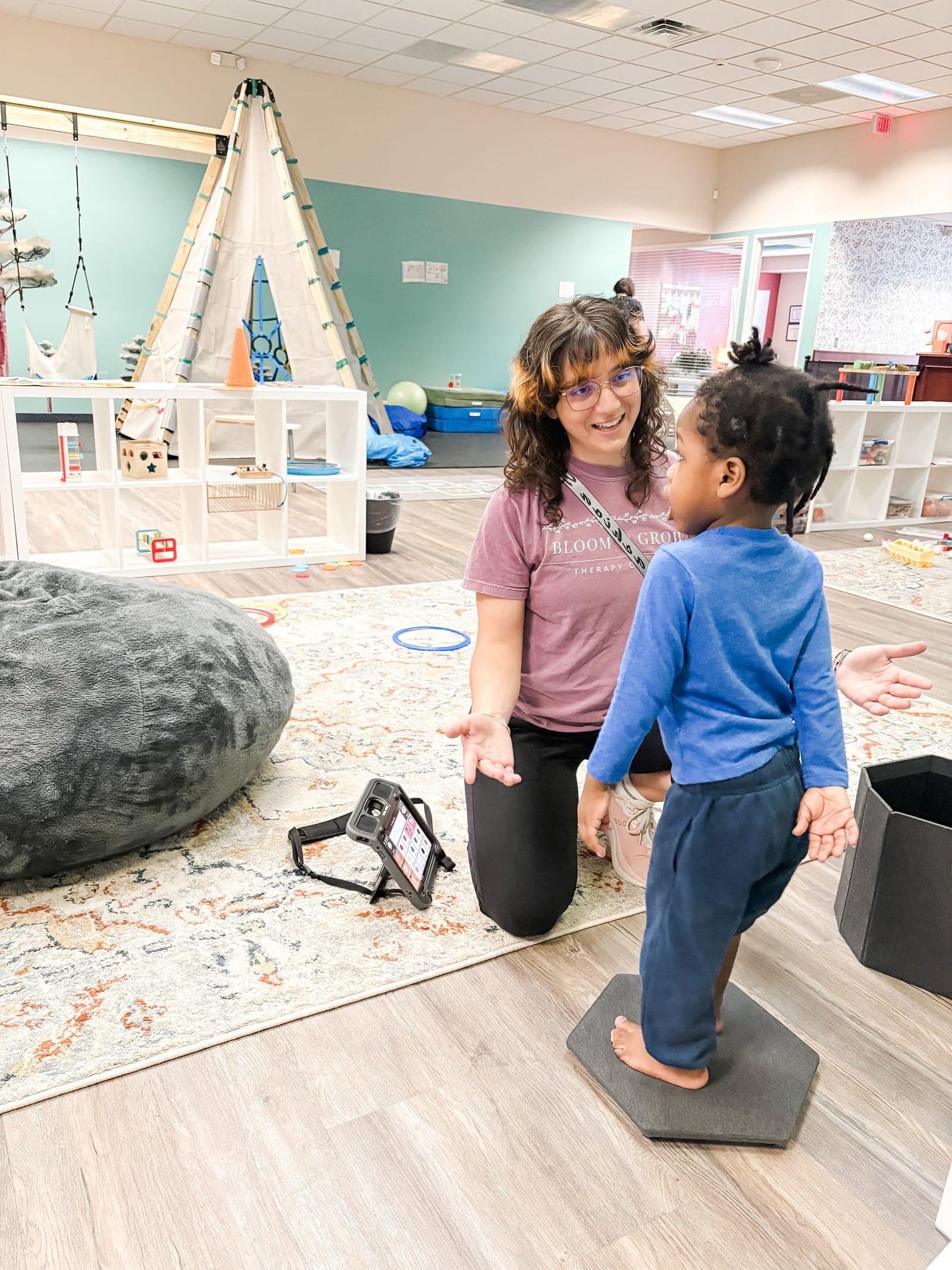 Therapist guiding toddler on balance board in gym