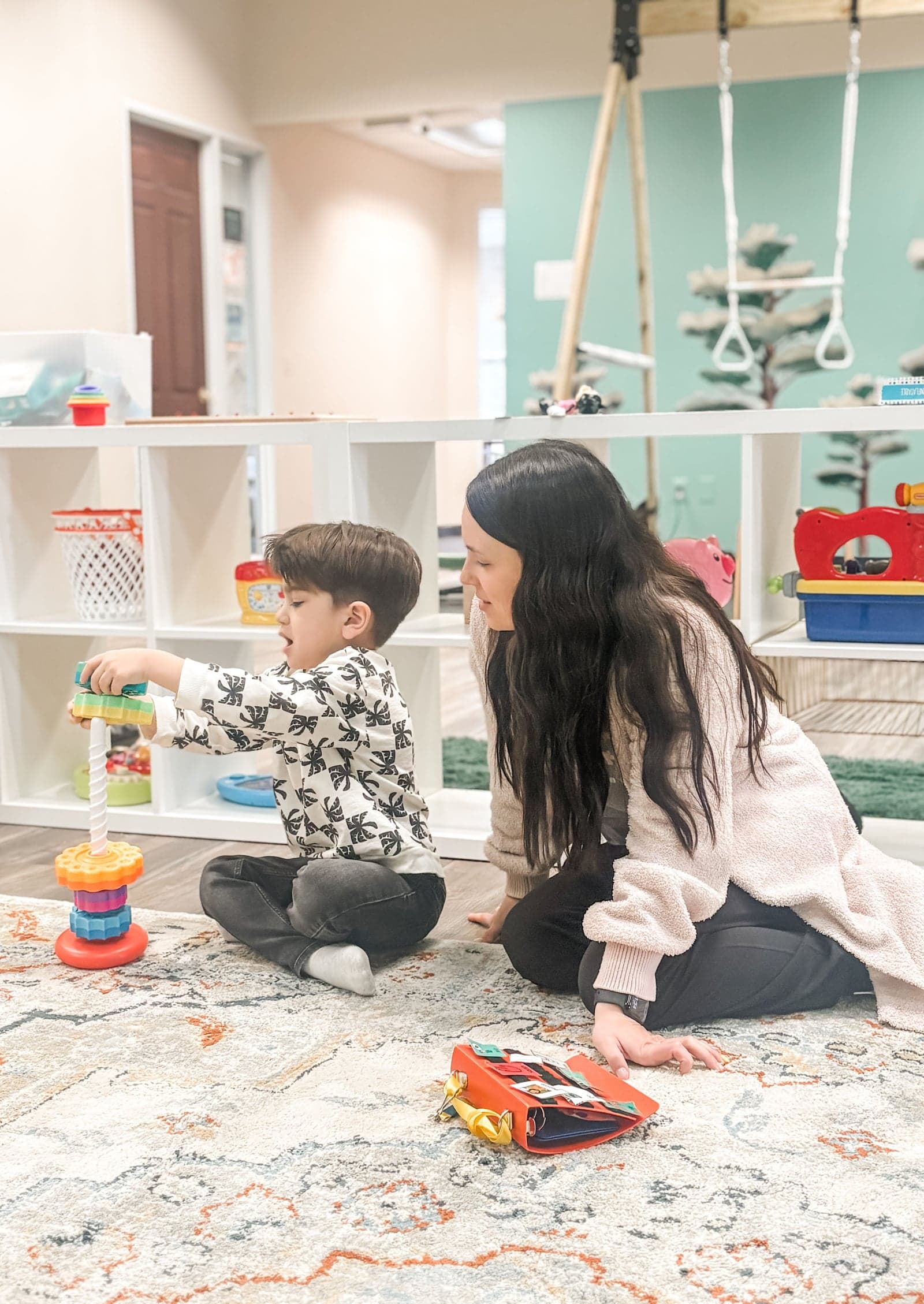 Toddler stacking blocks with therapist on floor
