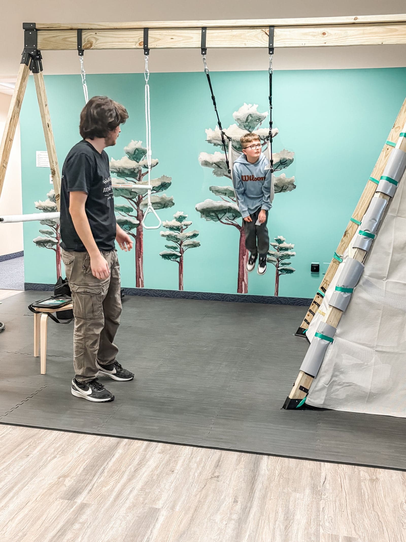 Therapist guiding child on gym swing
