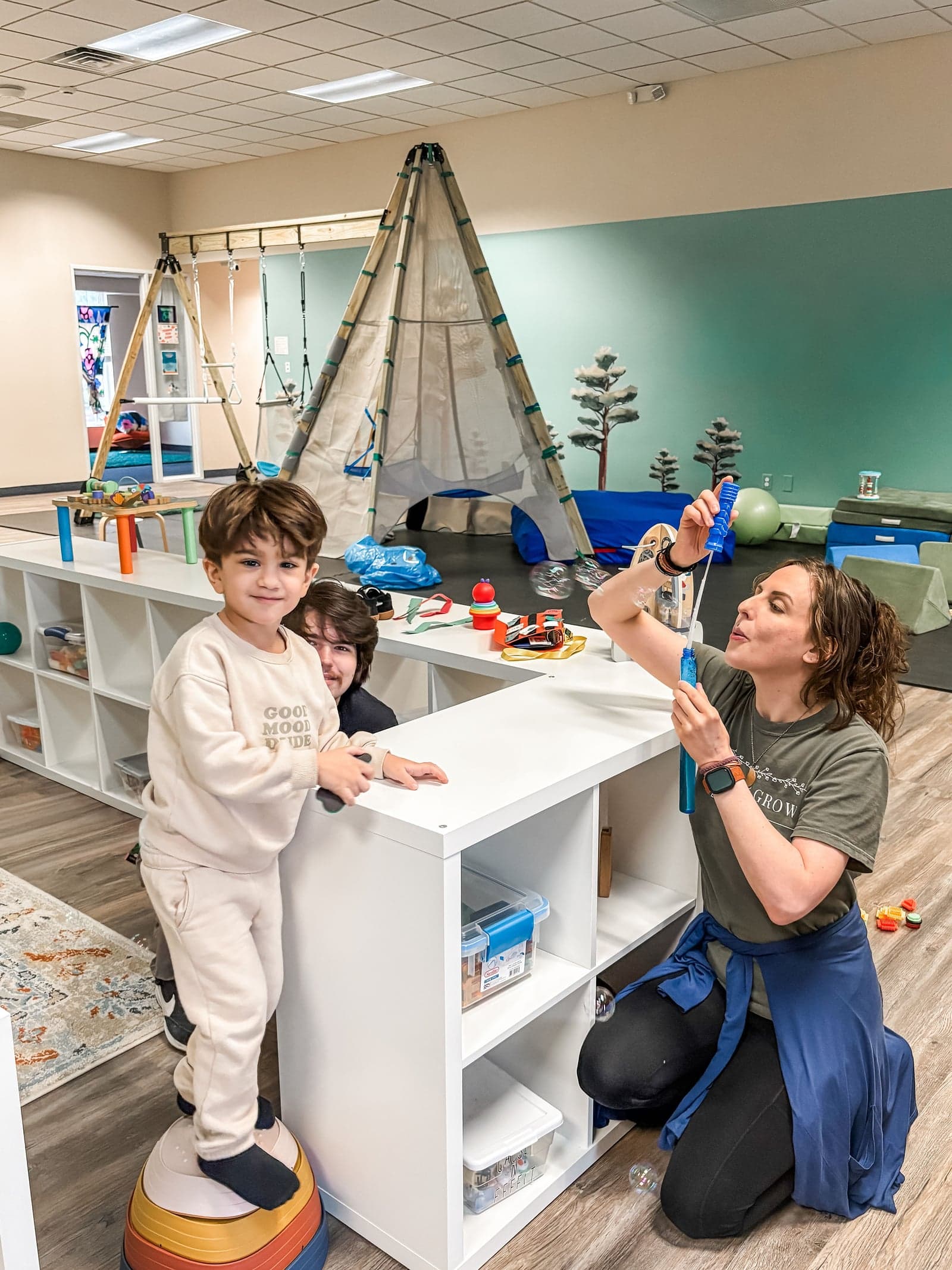 Therapy team engaging child with bubbles in gym